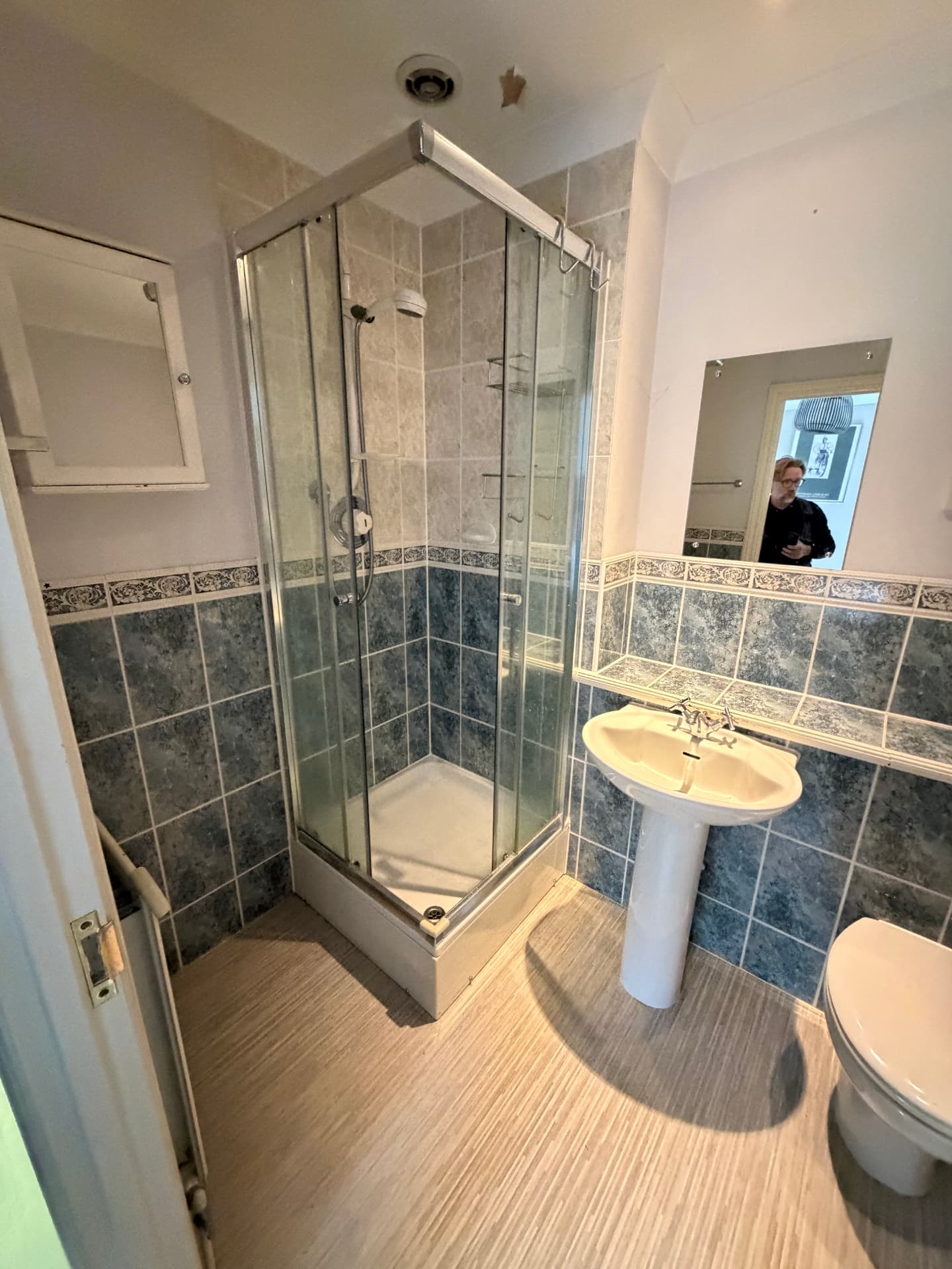 Old bathroom with dated shower cubicle and pedestal sink